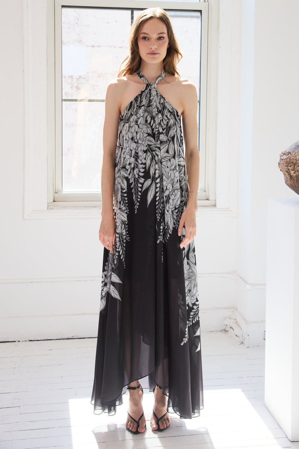 Woman wearing a black and white floral halter neck dress in a bright room.