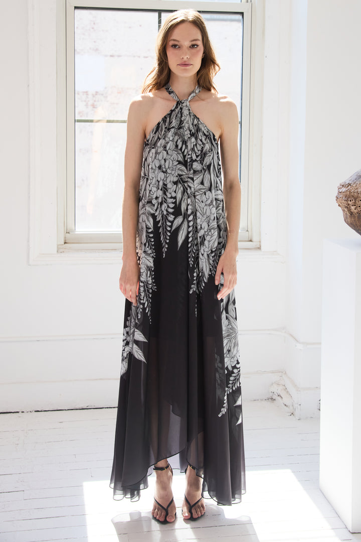 Woman wearing a black and white floral halter neck dress in a bright room.