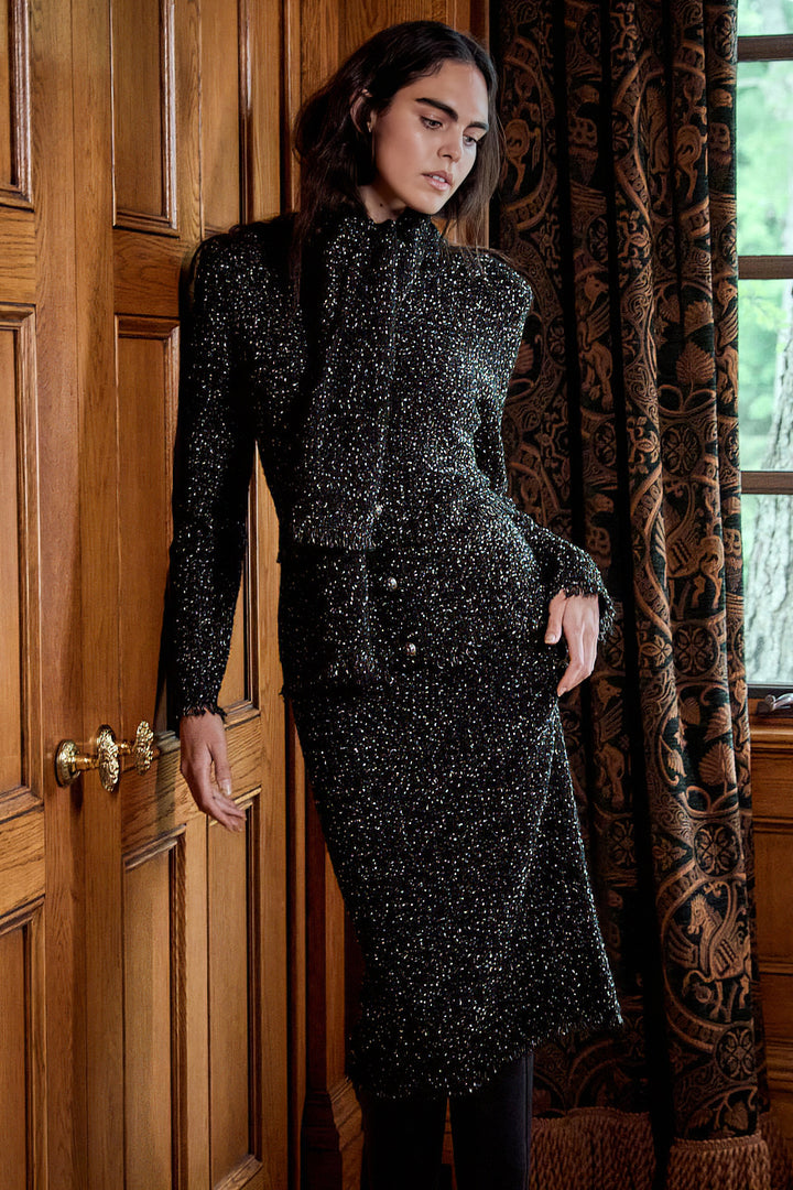 Relaxed-fit tweed cardigan with button front, ribbed cuffs, and hem; classic silhouette; editorial setting.