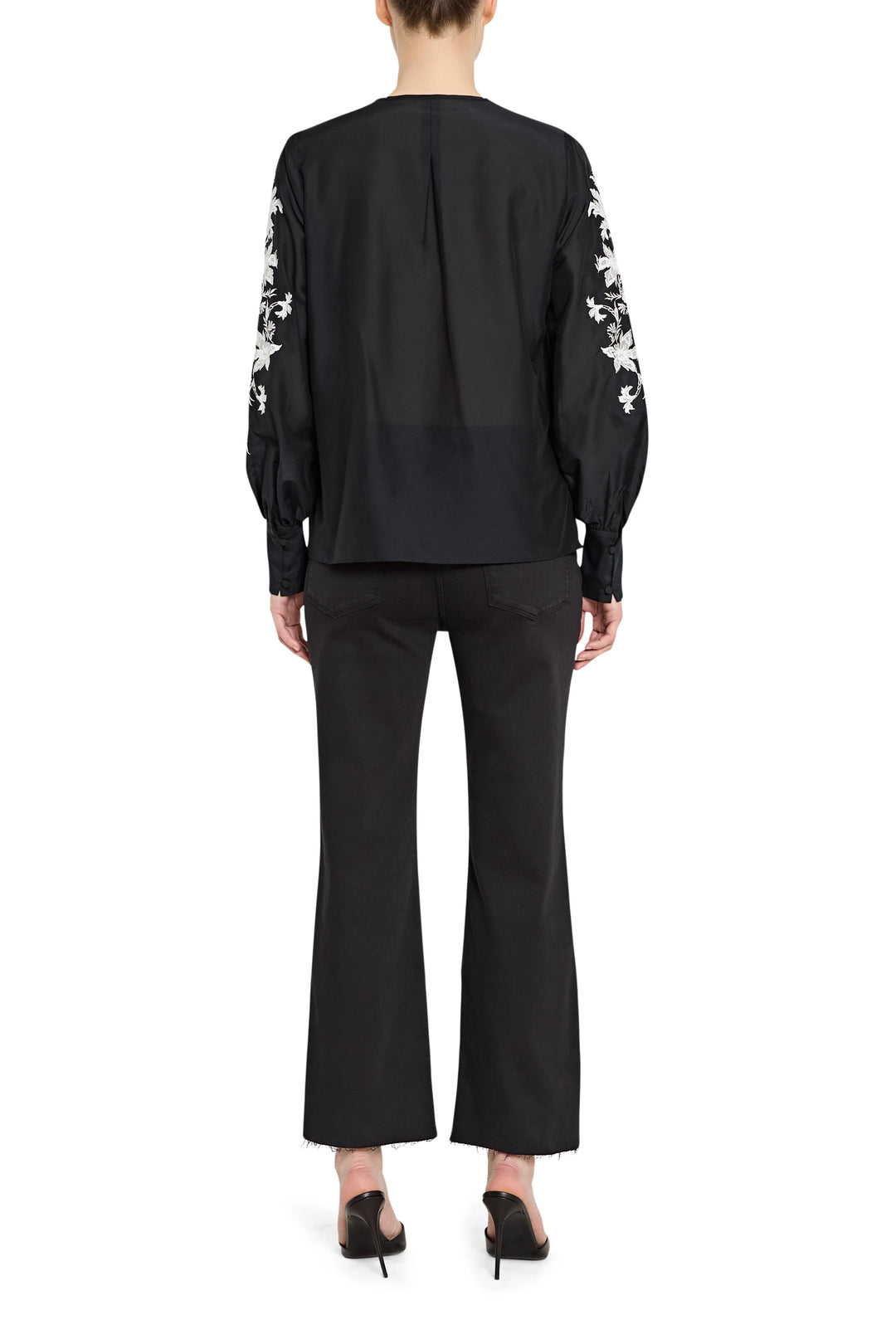 Black outfit with white floral embroidery on sleeves against a white background