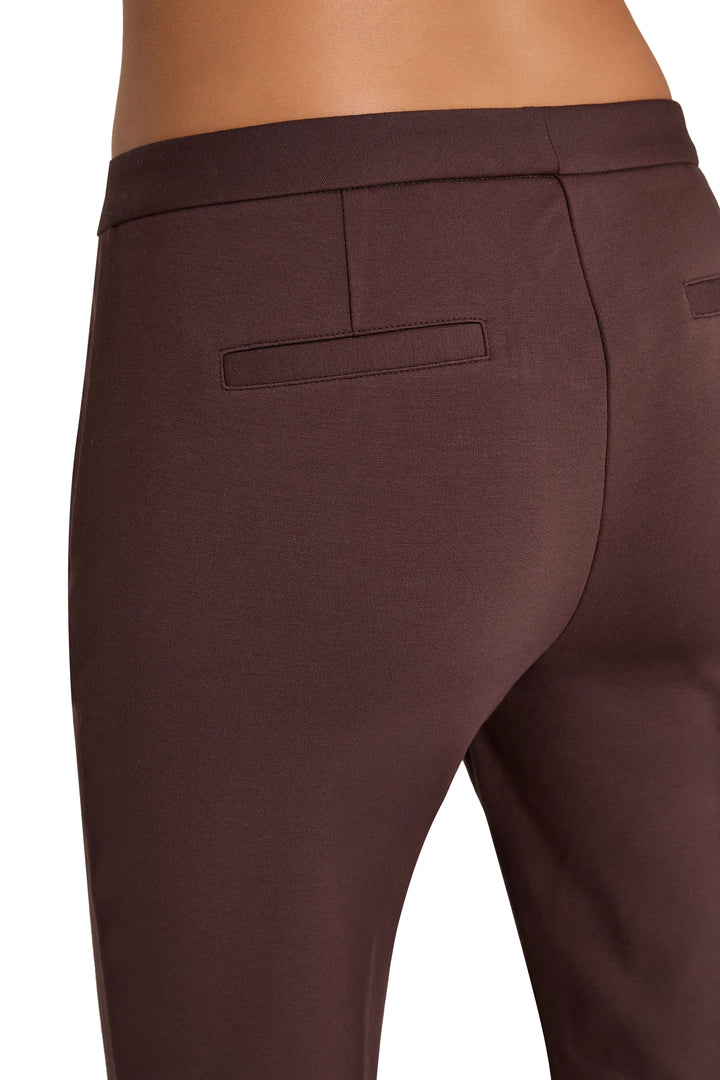 Welt pockets and tailored seams on knit pant, fitted cigarette silhouette. Back view on model.