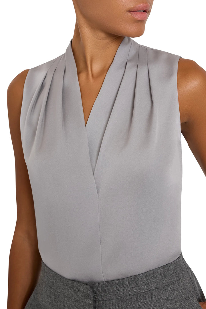 Sleeveless silk blouse with v-neck, pleated front, straight silhouette; front view on model.