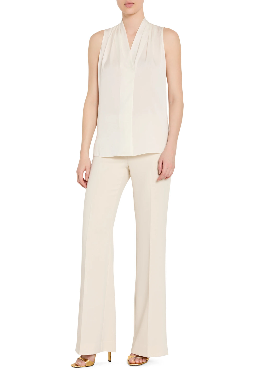 Woman wearing a white sleeveless top and pants on a white background