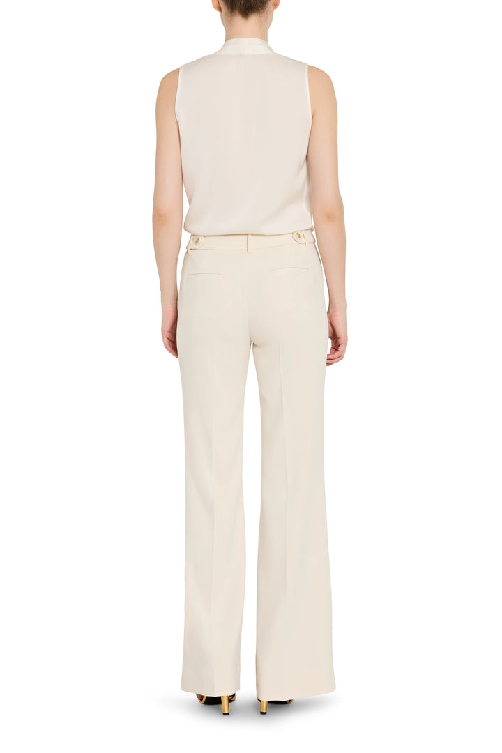 Person wearing a sleeveless beige top and high-waisted pants on a white background