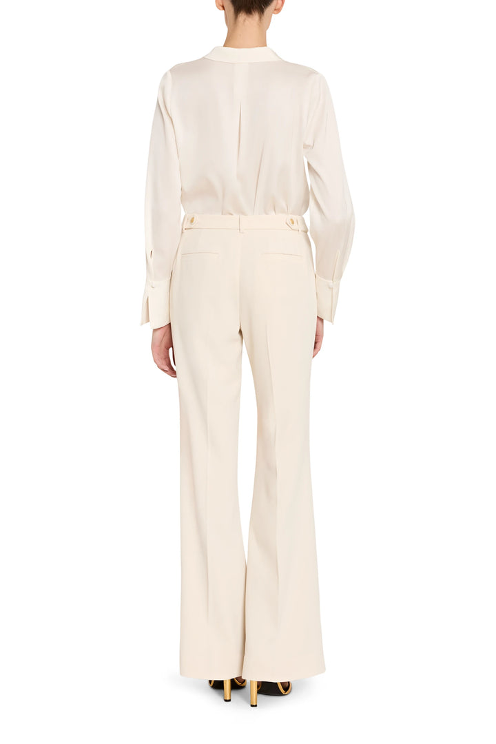 Person wearing a white blouse and cream pants on a white background