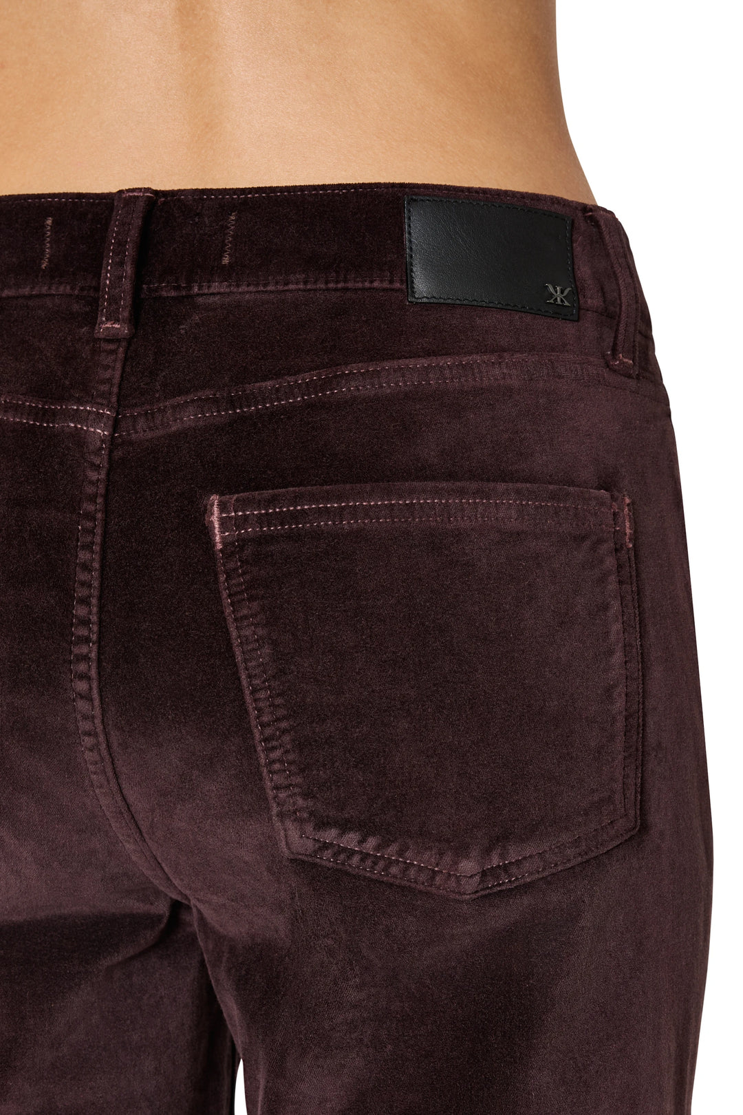 Detail of waistband, back pocket, and black label patch on stretch velvet pant. Detail view.