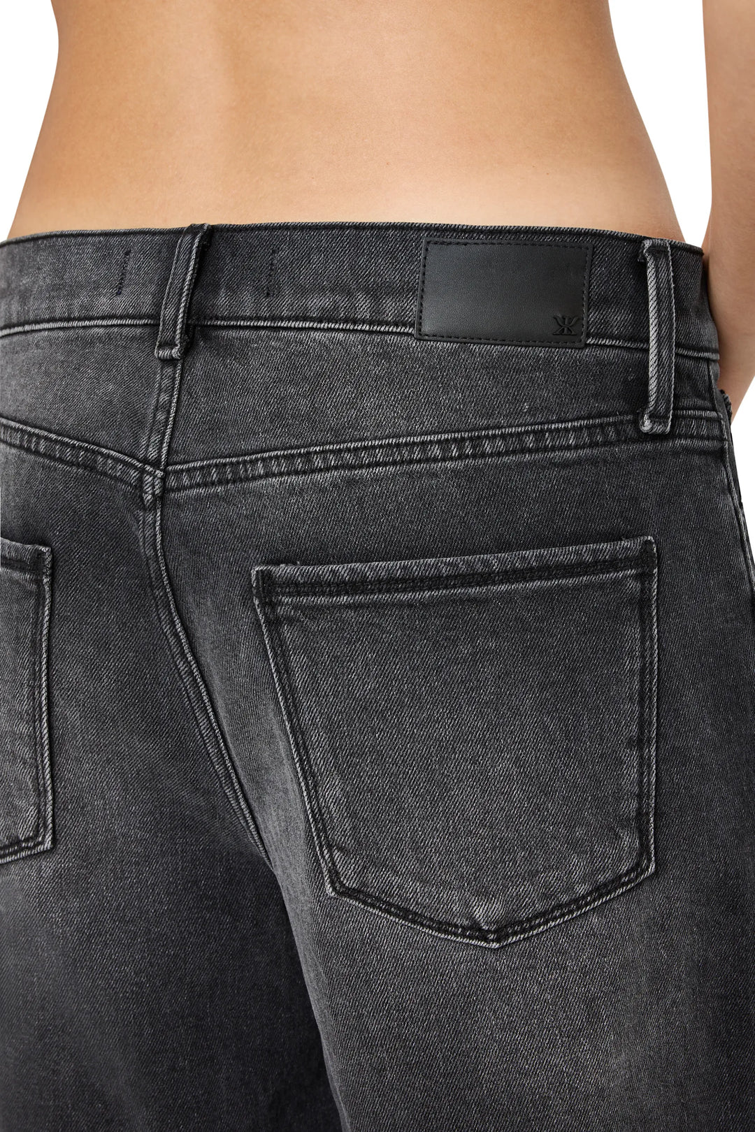 Cropped flare jean with raw-edge hem, fitted waistband, visible brand patch, denim construction; back view on model.