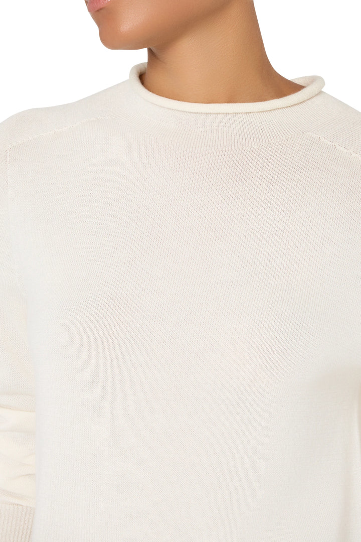 Mock neck sweater with streamlined silhouette and seamless knit construction, front view on model.
