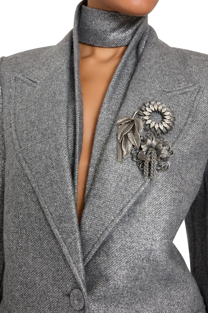 Brooch with metallic floral embellishments, sculptural setting, pin fastening; front view on model.