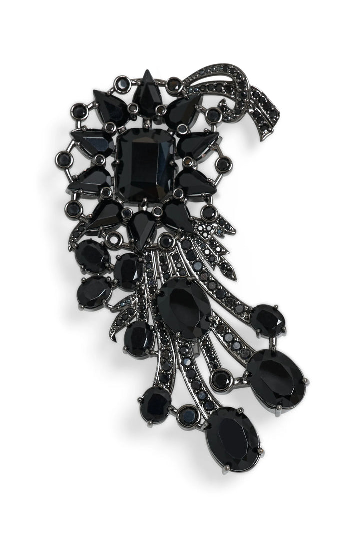 Sculptural crescent brooch with black stones on silver metal base, polished finish. Front view on white.
