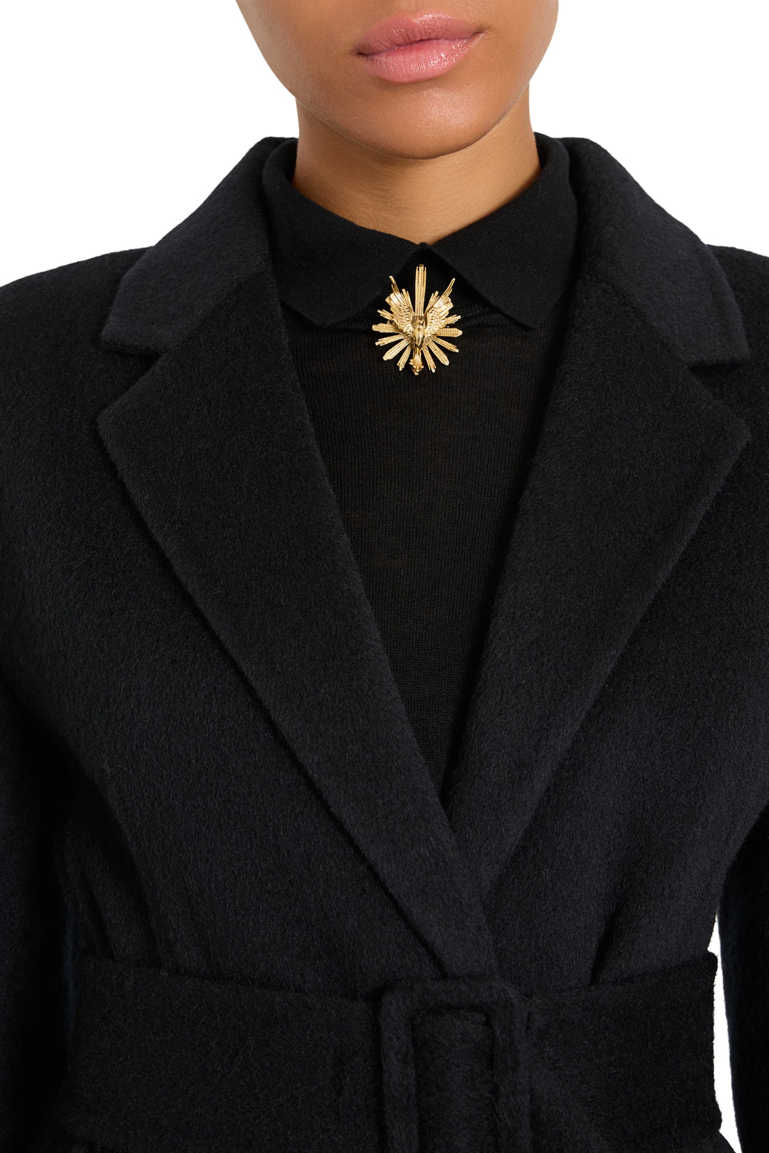 Round brooch with sculpted metal silhouette, intricate engraving detail at center. Front view on model.
