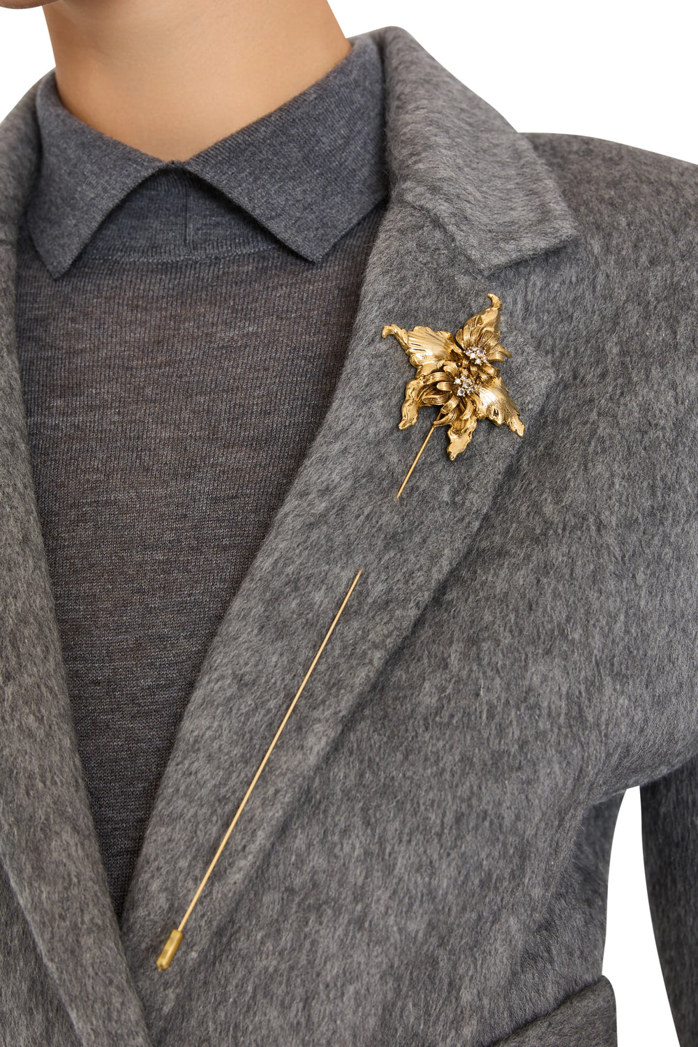 Wildflower-shaped brooch with sculpted petals and polished finish, intricate center detail; front view on model.