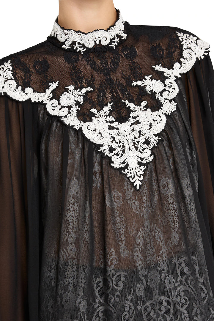 Sheer lace blouse with ornate white floral trim at neckline, classic silhouette. Front view on white.