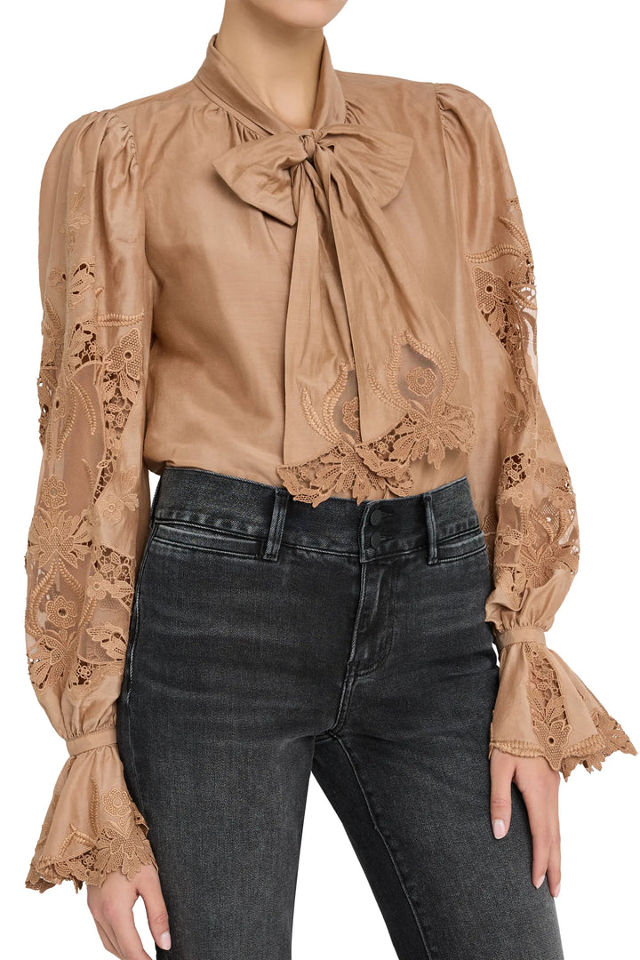 Sheer cotton blouse with hand-embroidered details, pintucked front, and voluminous sleeves; front view on model.