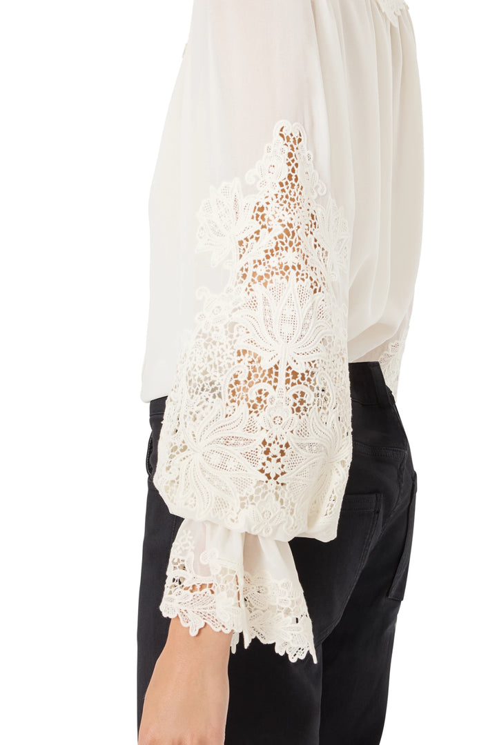 Side view on model of West Lacy Embroidered Blouse with lace-detailed sleeves, relaxed silhouette, and delicate embroidery.