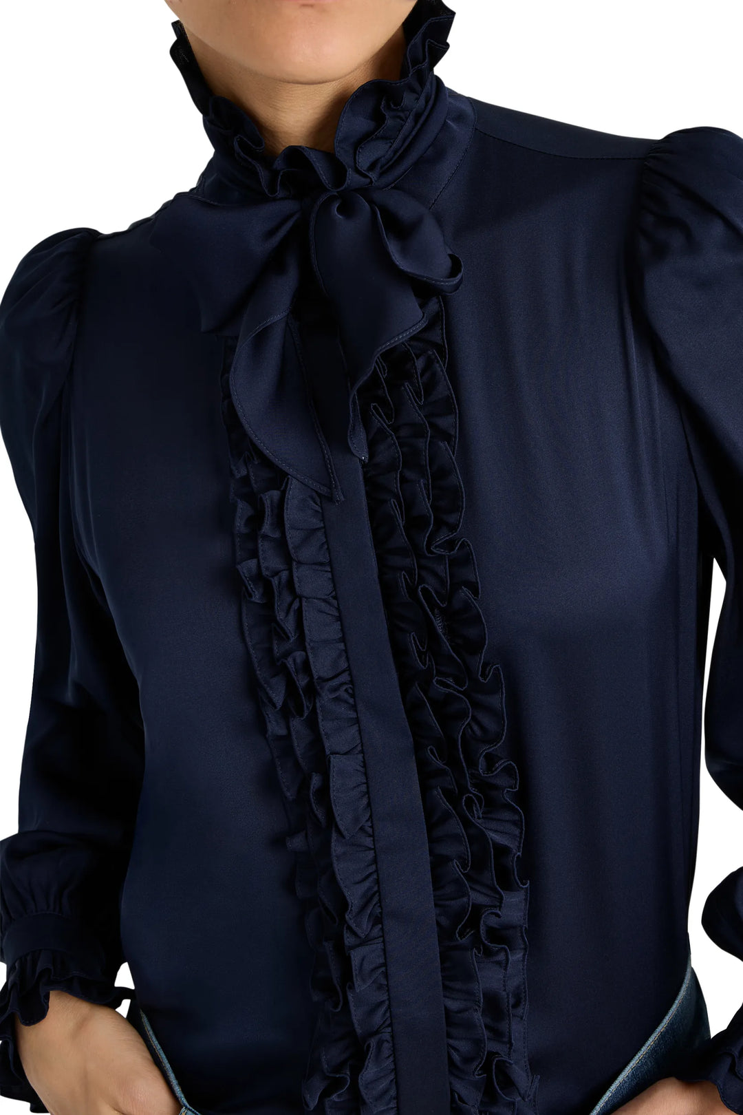 Silk blouse with romantic ruffles, high neckline, and tied bow. Relaxed silhouette. Front view on model.