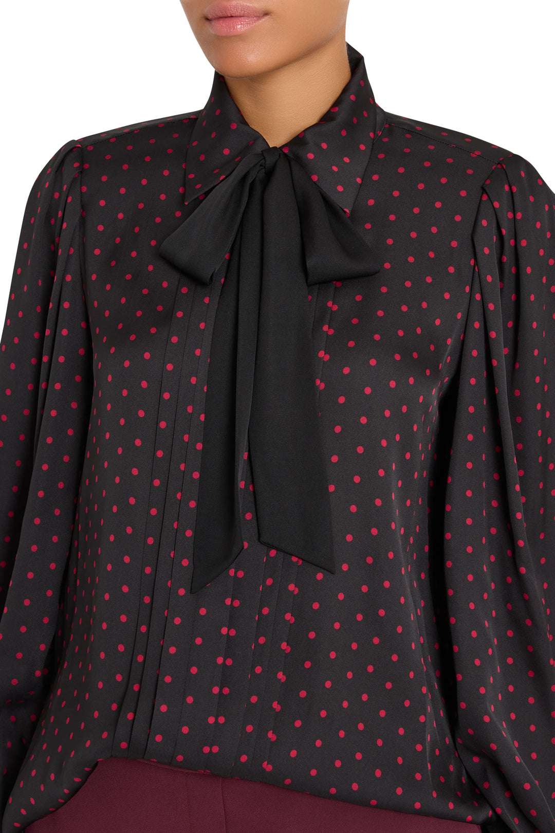 Silk blouse with polka dot print, stretch fabric, bold bow at black collar; straight silhouette. Front view on model.