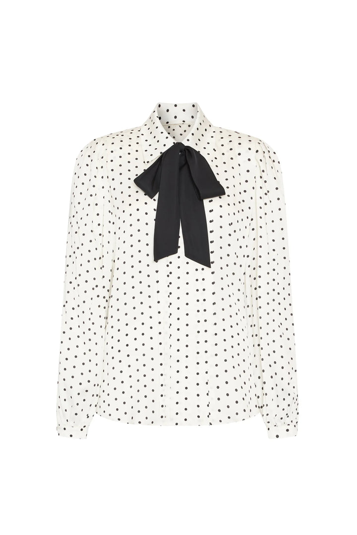 Silk blouse with long sleeves, buttoned cuffs, polka dots, oversized bow at collar; front view on white.