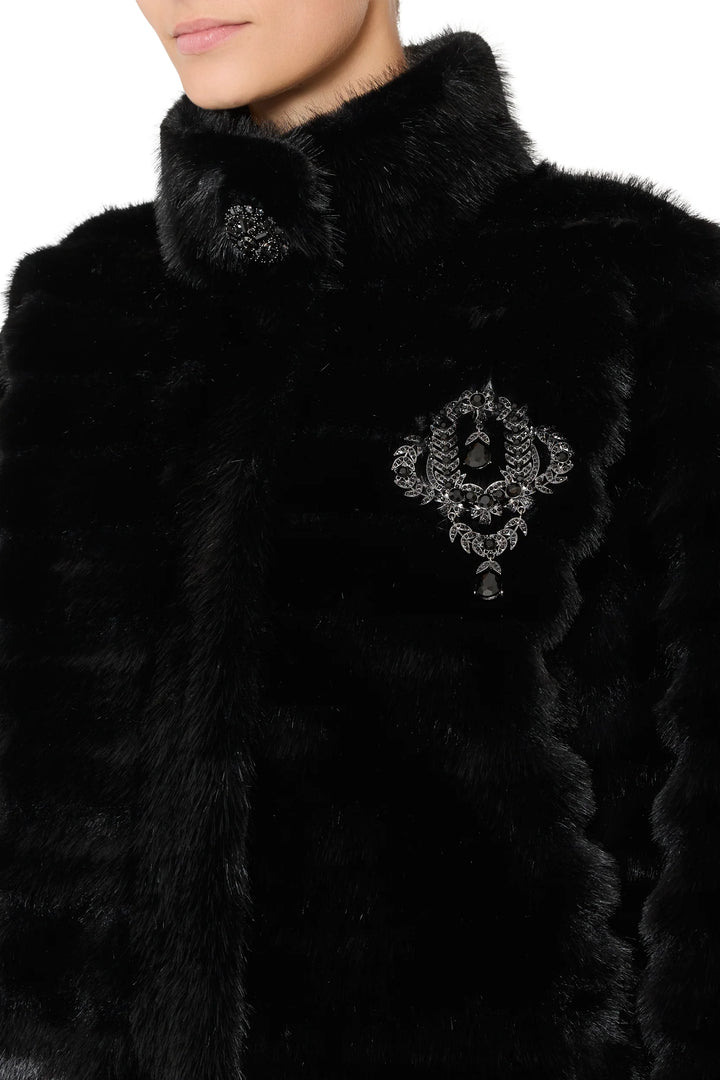 Long faux fur coat with vintage stripes, jeweled black brooches at collar and chest. Front view on model.