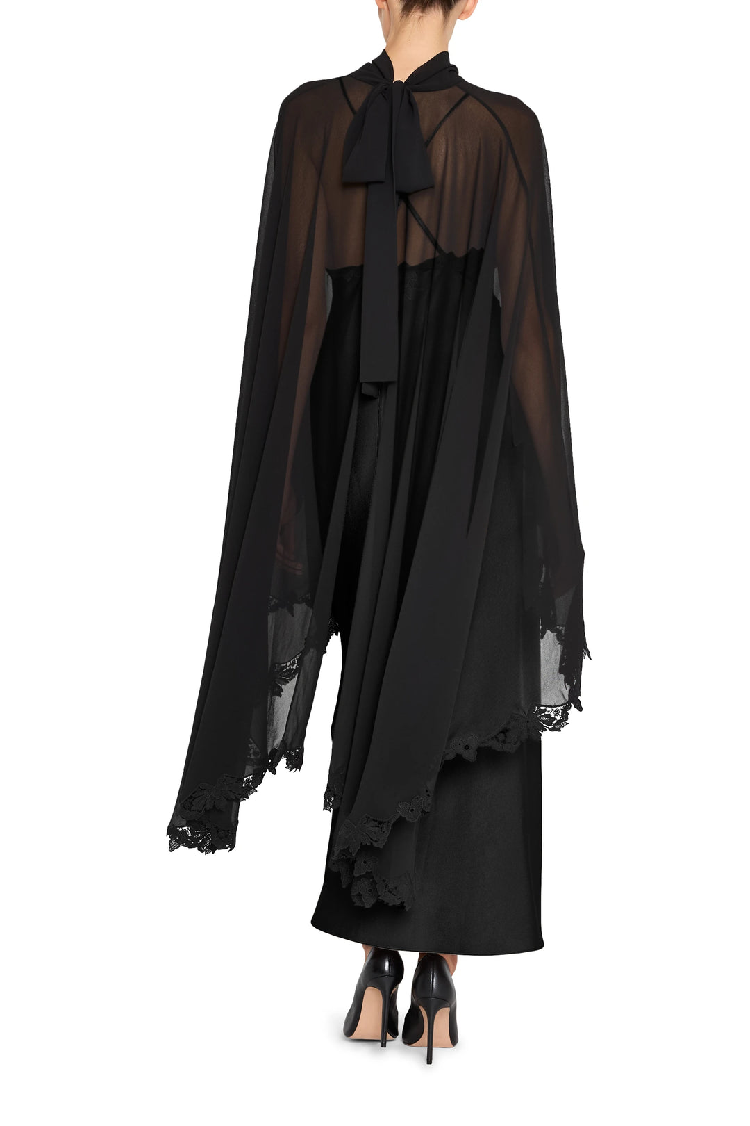 Sheer cape with lace trim and bow detail, draped silhouette, fluid fabric; back view on model.