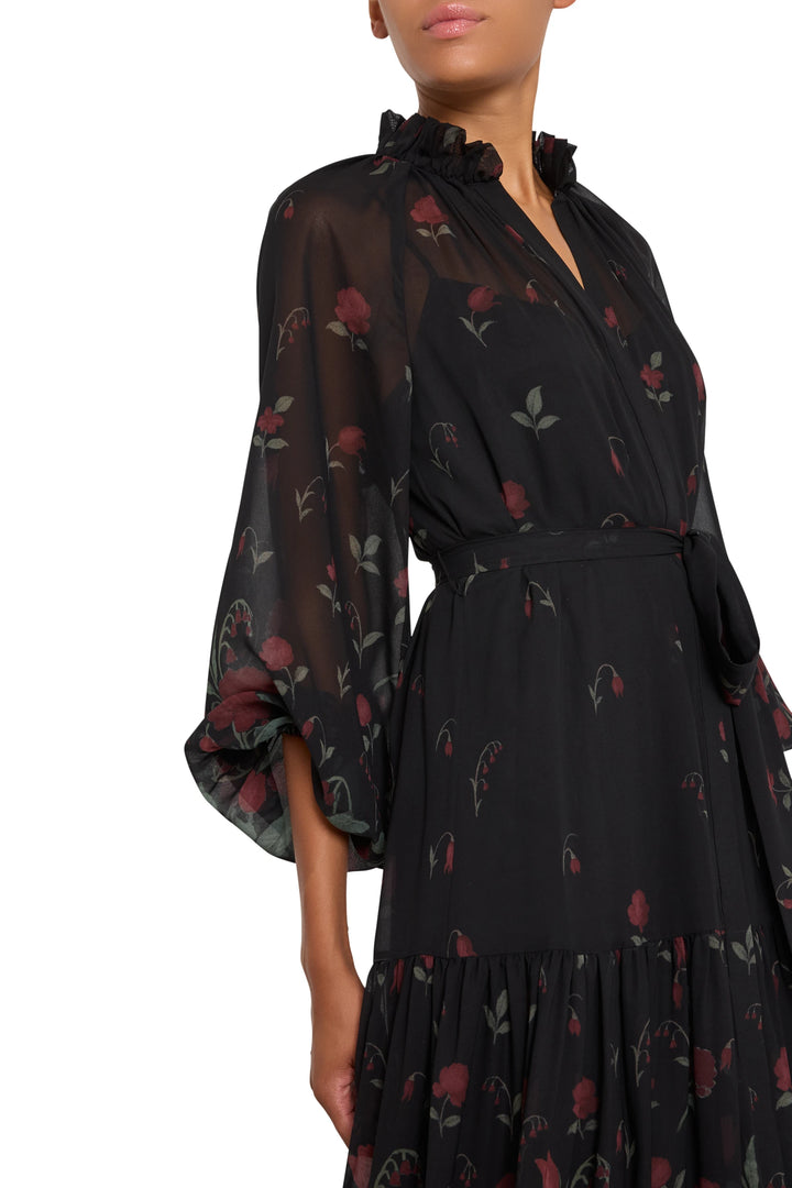 Black floral chiffon dress, ruffled collar, tiered skirt, waist belt; fluid silhouette. Front view on model.