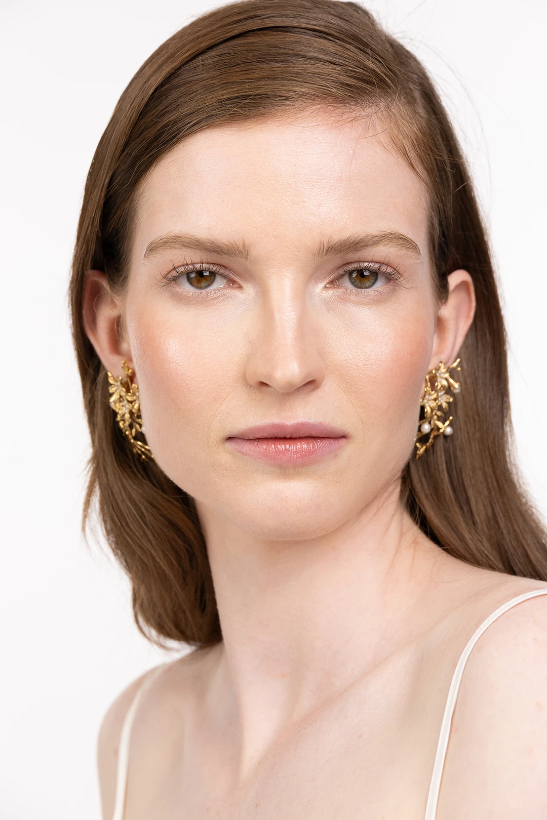 Drop earring silhouette with geometric forms, minimalist metalwork. Front view on model.