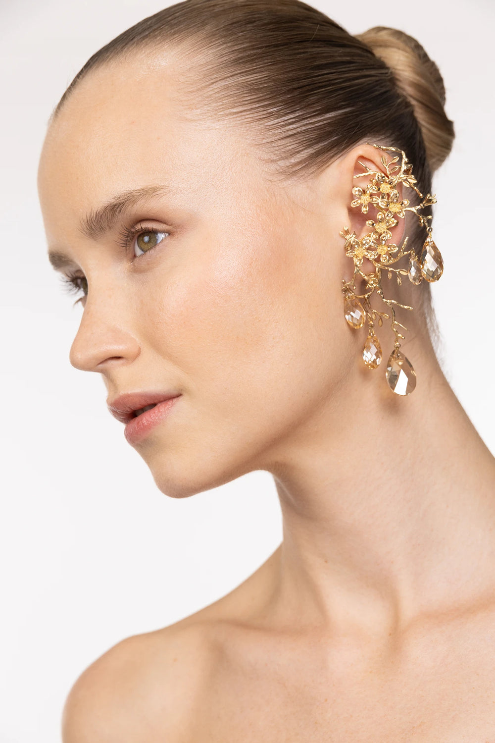 Sculptural drop earring with intricate metallic construction. Side view on model.