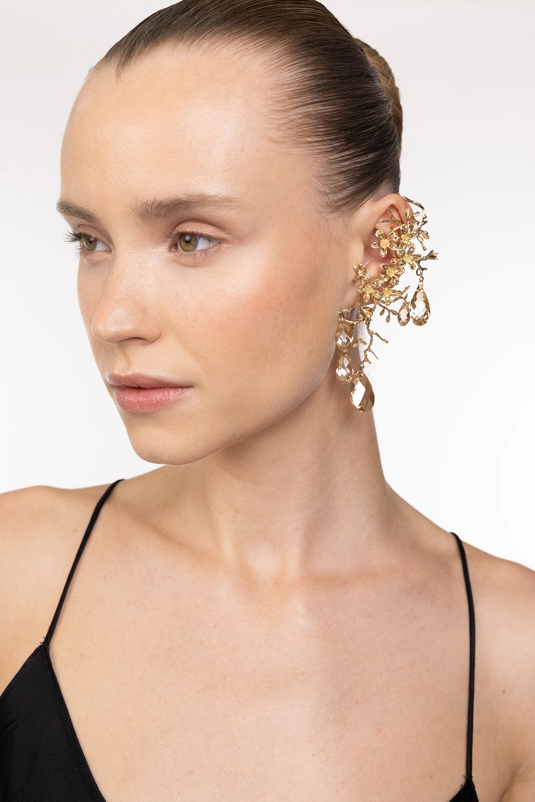 Drop earring with floral motifs and crystal embellishments, featuring delicate sculpted construction; front view on model.