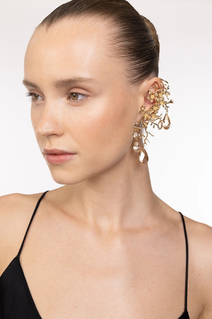 Drop earring with floral motifs and crystal embellishments, featuring delicate sculpted construction; front view on model.