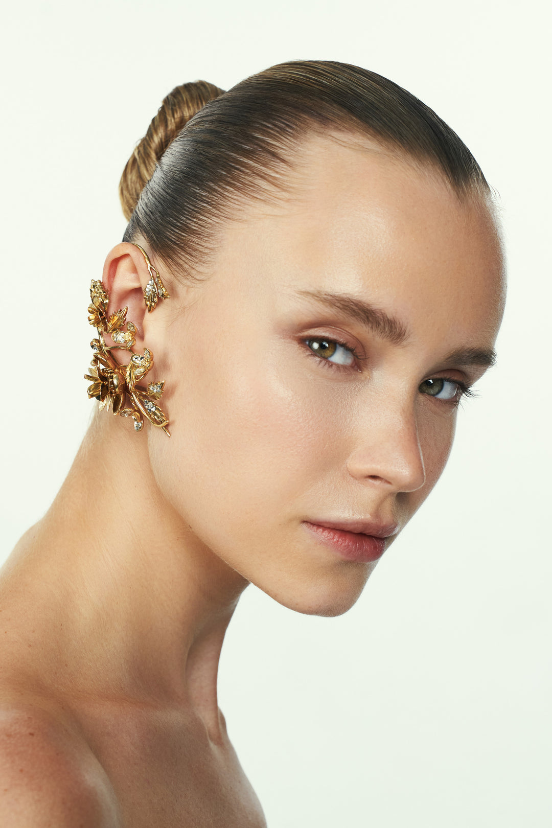 Sculptural, nature-inspired ear cuff with curved metal silhouette and organic detailing, side view on model.