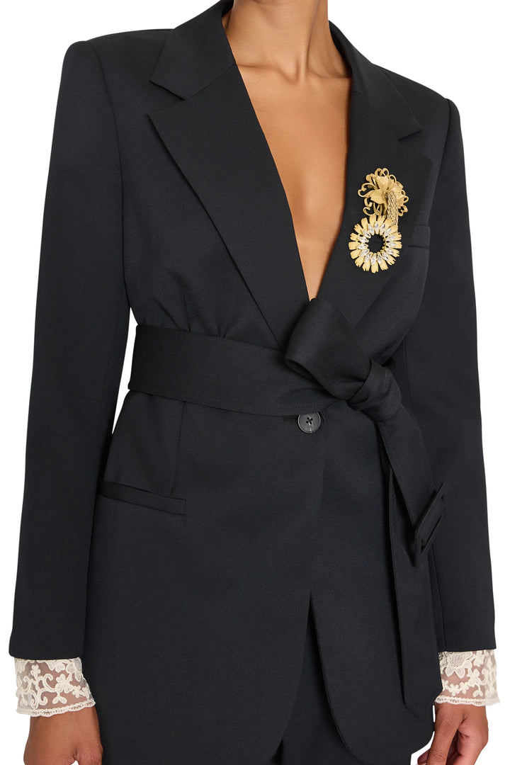 Jillian Jeweled Belted Blazer in black tropical wool with peaked lapels, waist tie, brooch, and lace cuffs. Front view.
