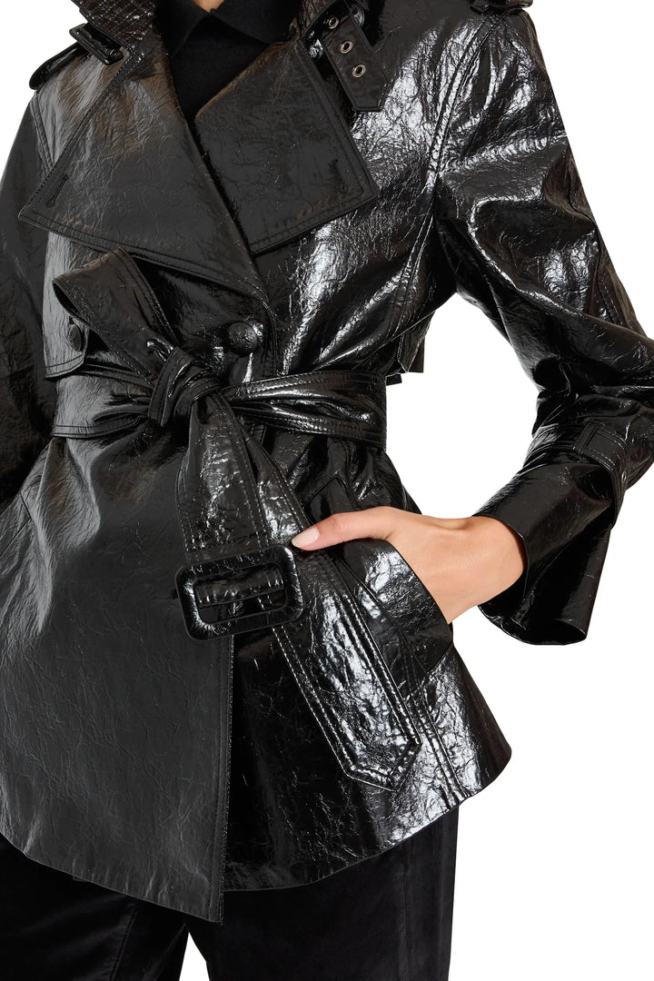 Cropped trench with structured silhouette and classic lapel in vegan leather, waist pockets. Front view on model.