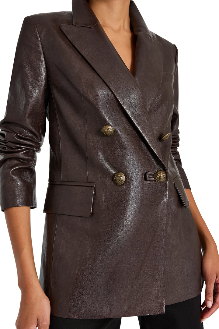 Double-breasted vegan leather blazer, military buttons, structured fit, peak lapels; front view on model.
