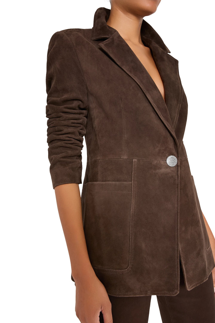 Suede blazer with elongated silhouette, roomy front pockets, tailored construction; front view on model.