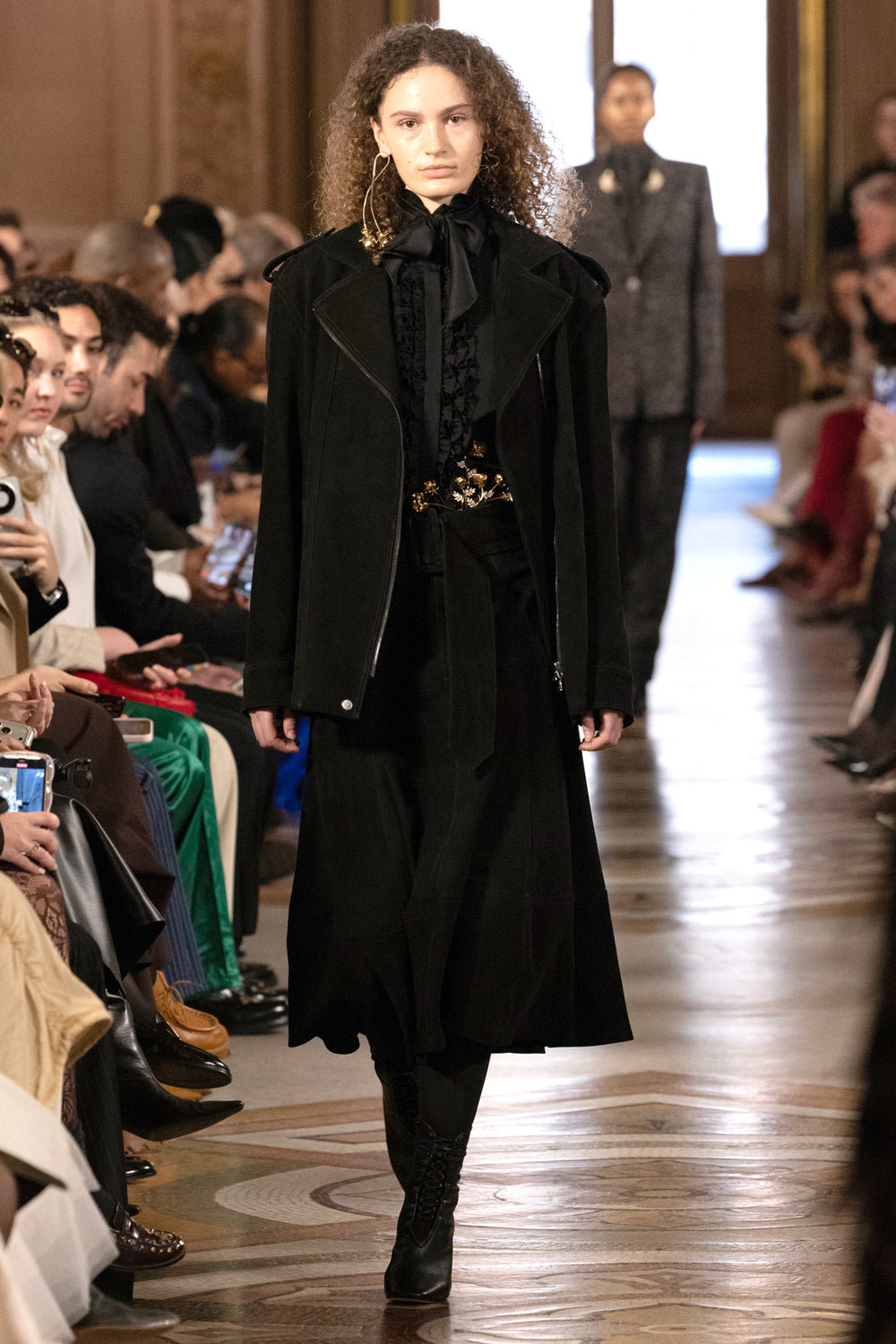 Suede moto jacket with structured shoulders, zip front, and notch collar; editorial setting on model.