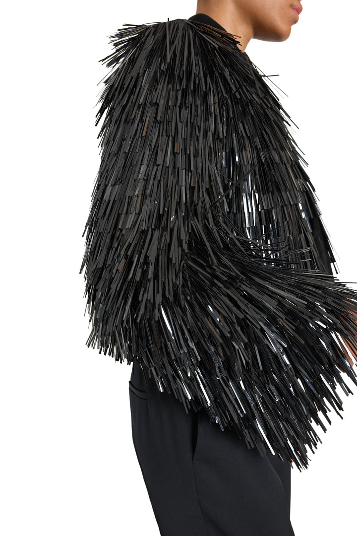 Boxy sequin jacket with shiny fringe strips from shoulders to hips. Front view on model.