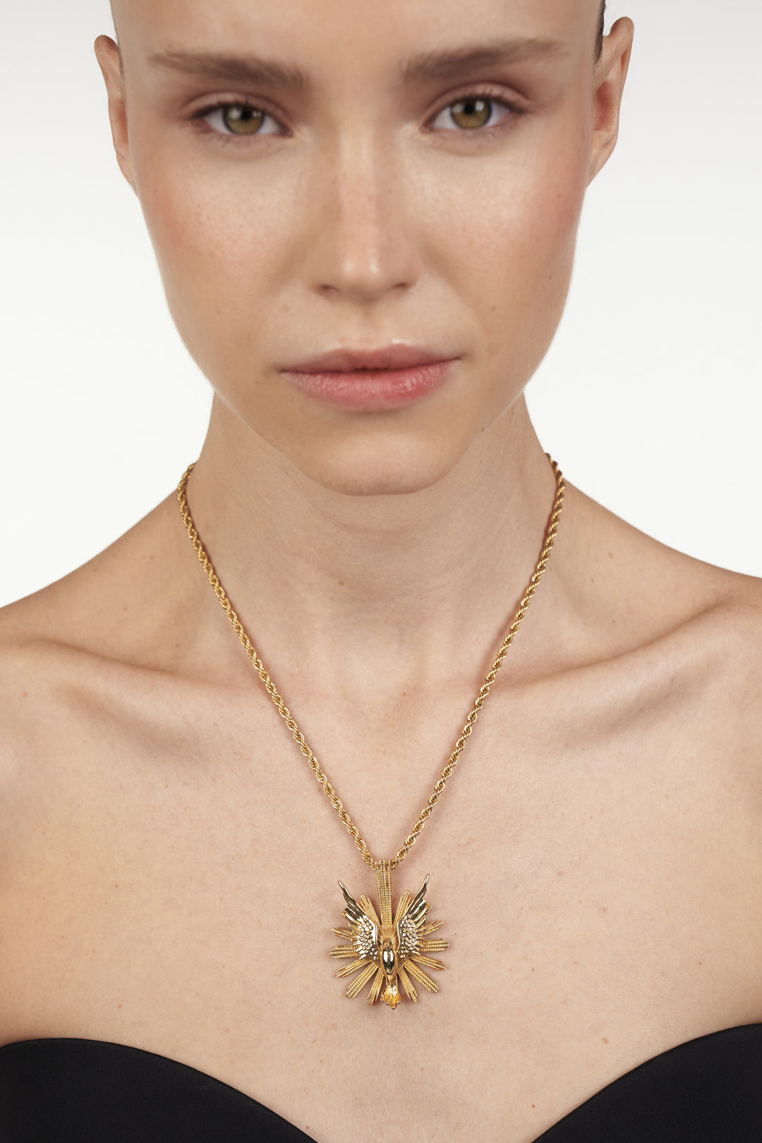 Kiwi Necklace, circular sun pendant with polished surface and detailed rays; front view on model.