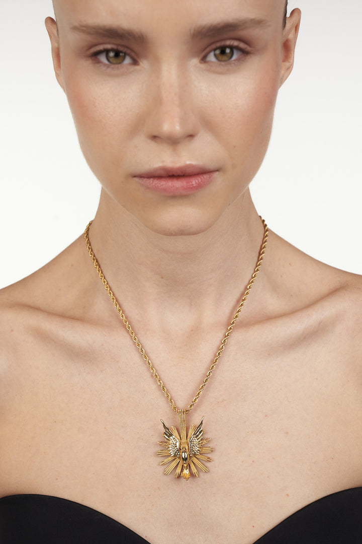 Kiwi Necklace, circular sun pendant with polished surface and detailed rays; front view on model.