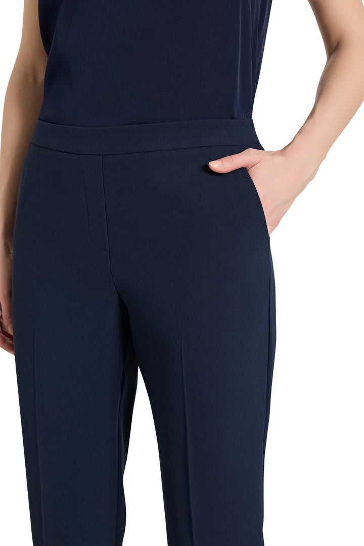 Ankle-length crepe pant with pull-on waist, slim silhouette, angled side pockets; front view on model.