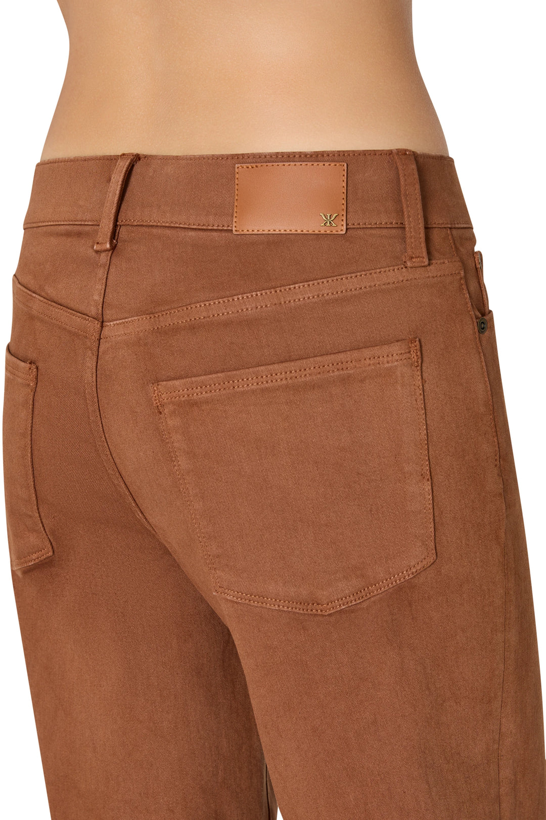 Detail of mid-rise coated denim, showing back pocket stitching and leather patch; detail view.