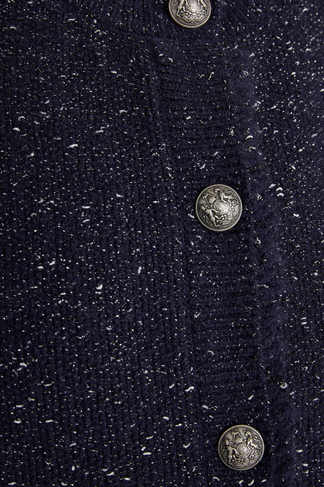Detail of Lilah Sweater Vest showcasing speckled knit texture and ornate silver buttons. Detail view.