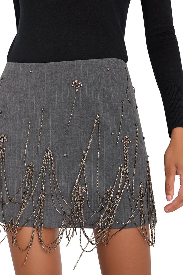 Mini skirt with fitted silhouette, structured pinstripe fabric, embellished details; front view on model.