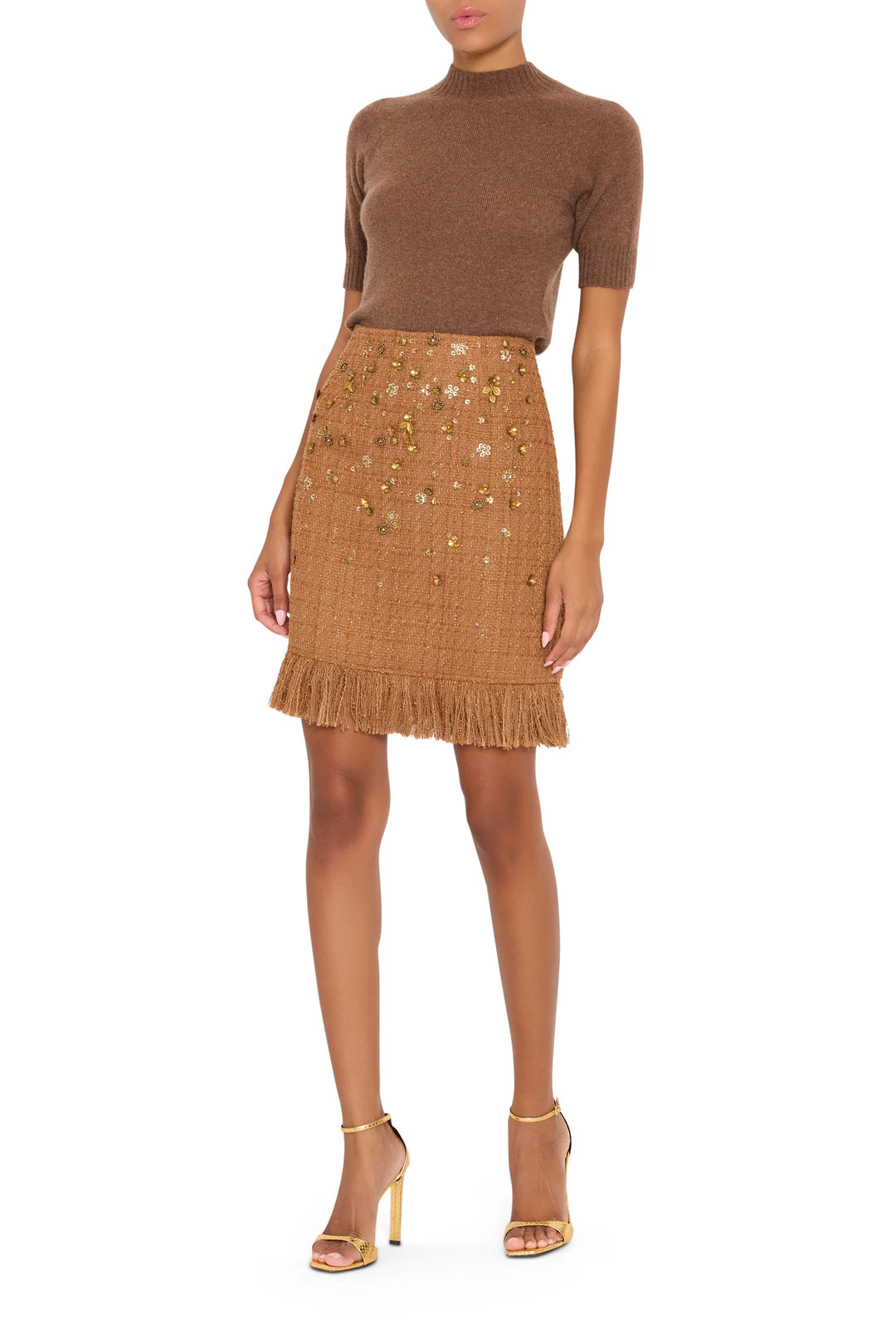 A-line tweed skirt with fringe hem and gold accents, structured fit. Front view on model.