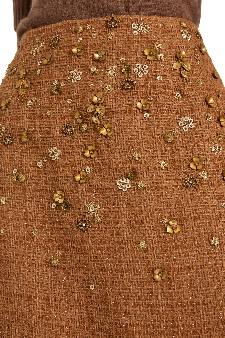 Detail of A-line tweed skirt with intricate gold and bronze floral beadwork, textured fabric; detail view.