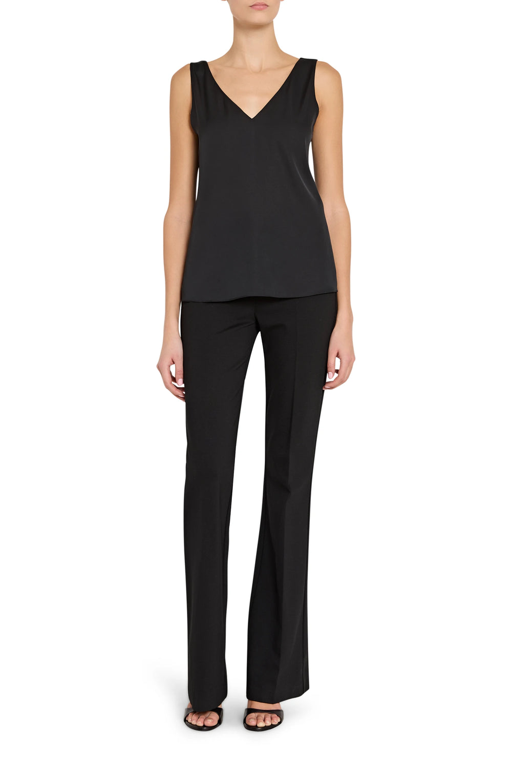 Person wearing a black sleeveless top and black pants on a white background