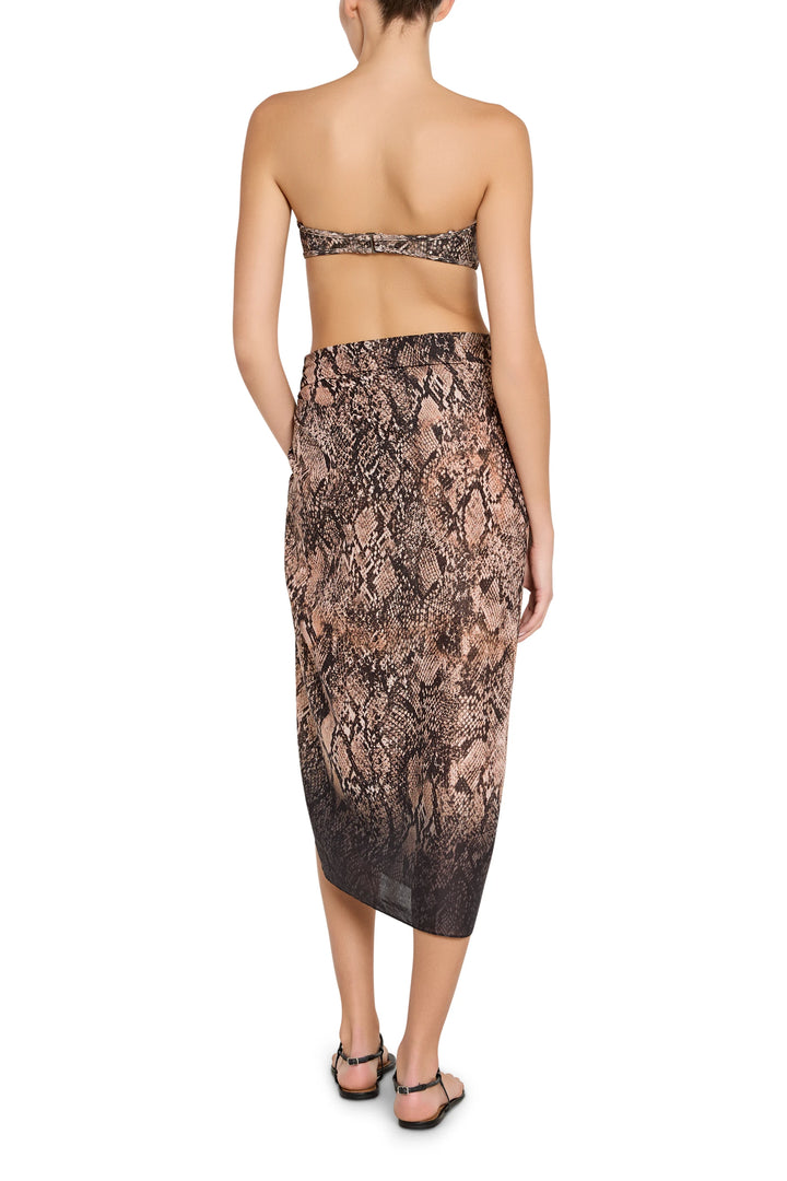 Woman wearing a strapless top and snake print skirt on a white background