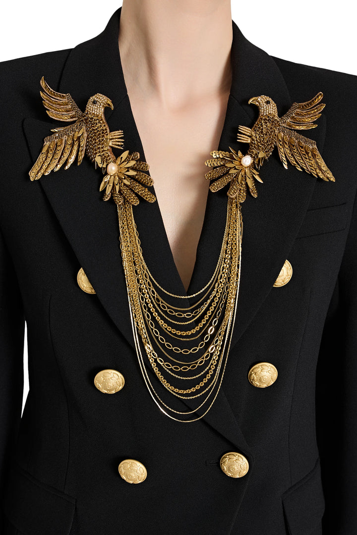 Black blazer with gold eagle designs and jewelry on a white background