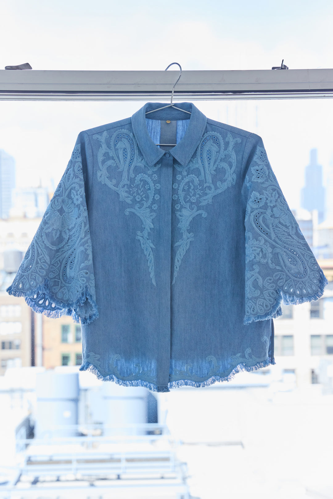 Boxy short-sleeve denim blouse with hand-embroidered detail, relaxed fit and soft cotton, front view on white.