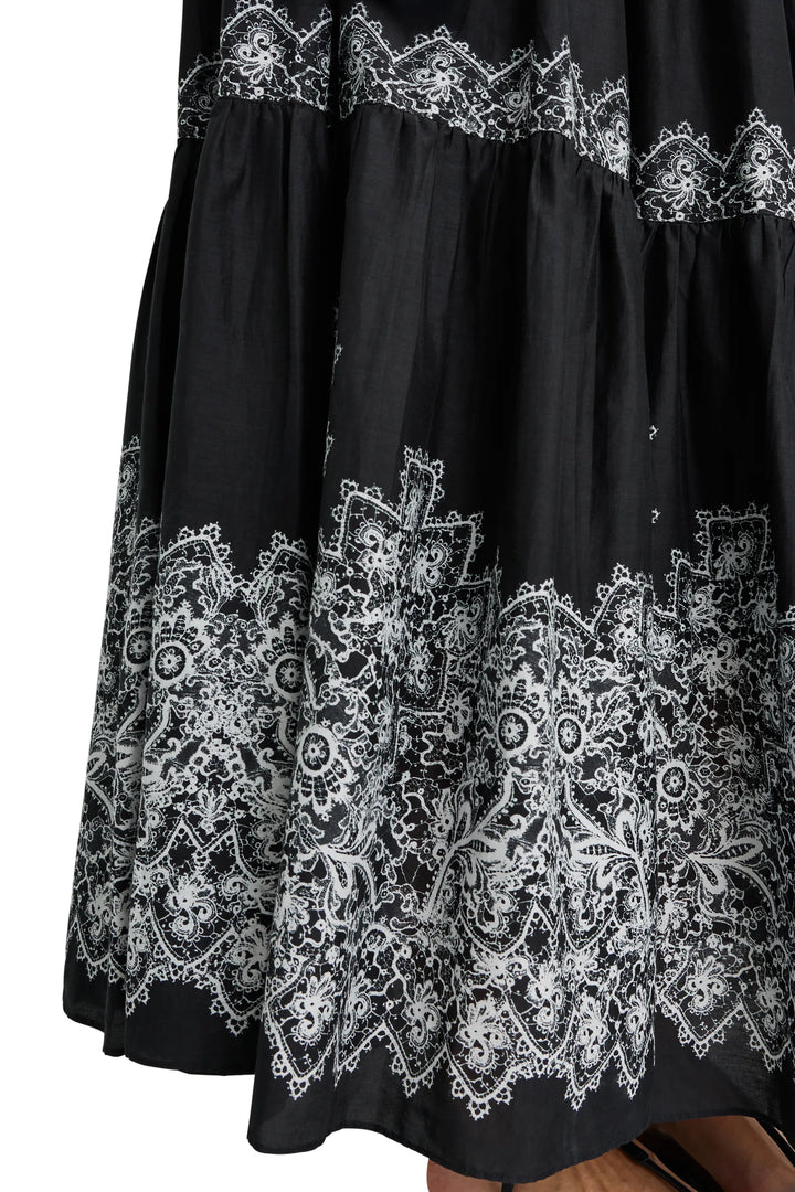 Maxi dress with fluid silhouette, white antique lace print at hem, partially sheer lower skirt; front view on model.