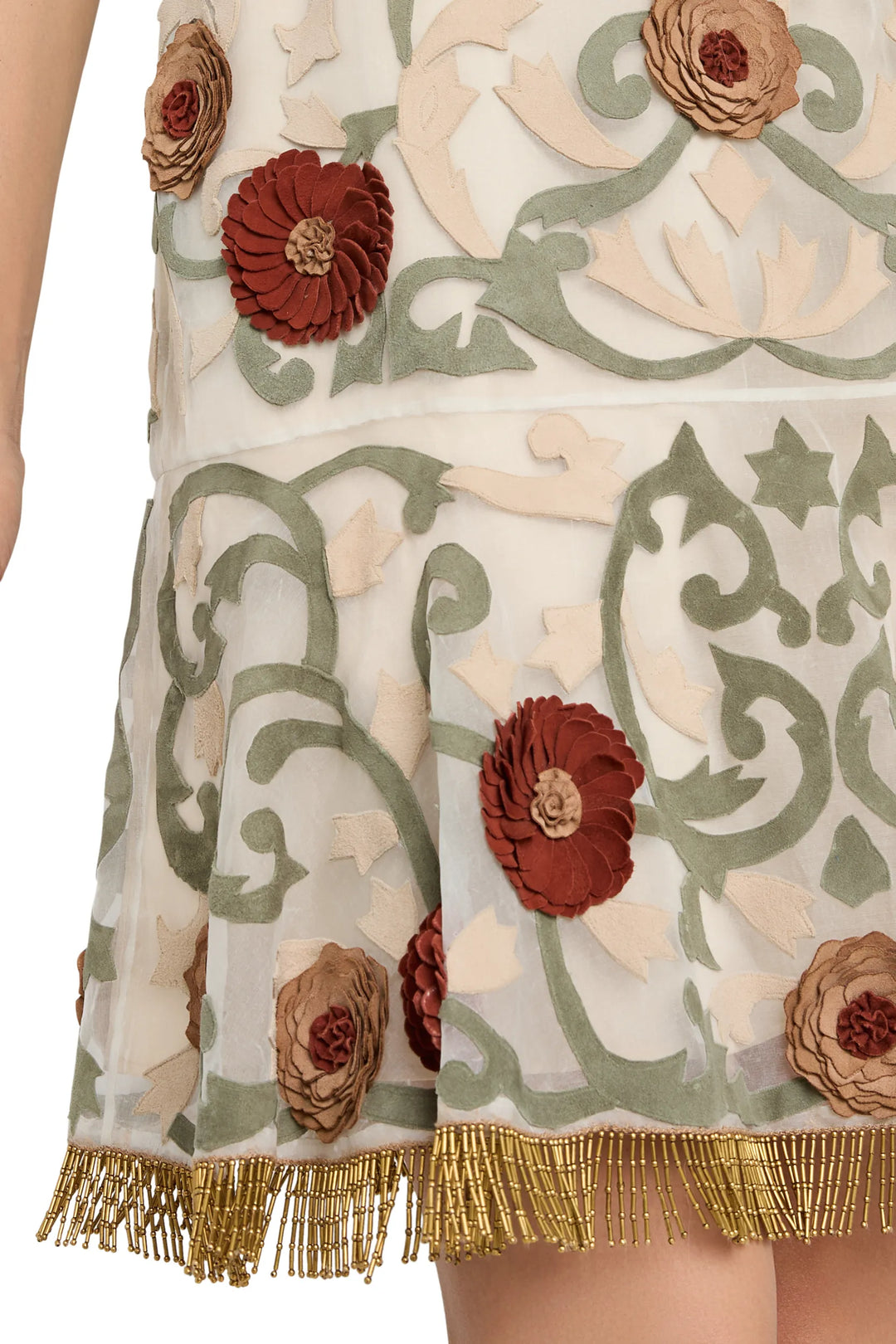 Sheer organza mini dress with appliqué, green embroidery, gold beaded fringe trim detail view.
